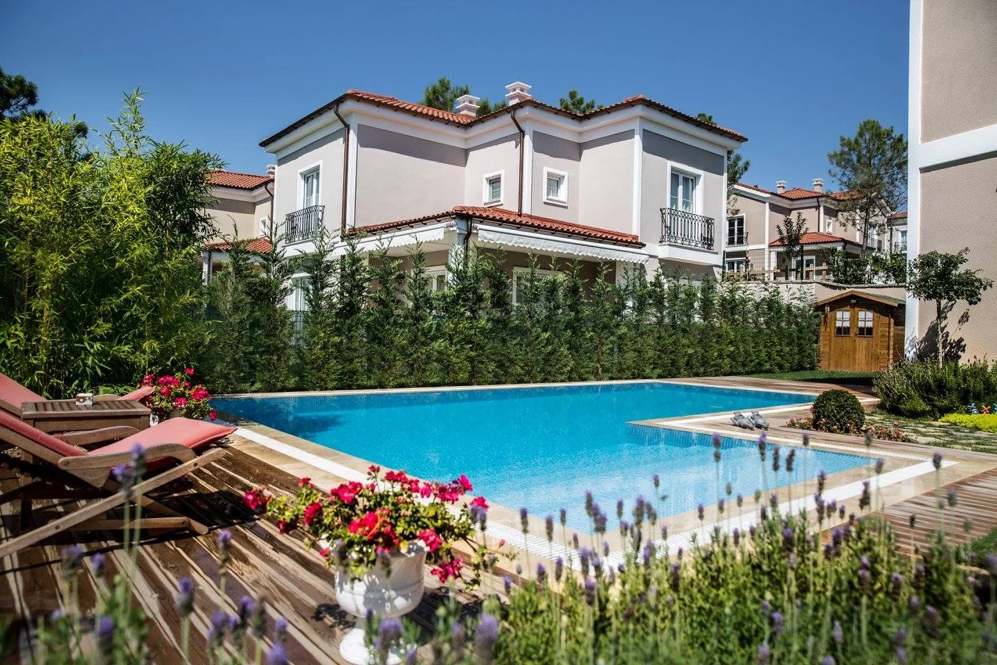 Ahşap deck ve taş kaplamayla çevrelenmiş bahçe havuzu — çevre düzenlemesi havuzla birlikte planlanmış bir uygulama