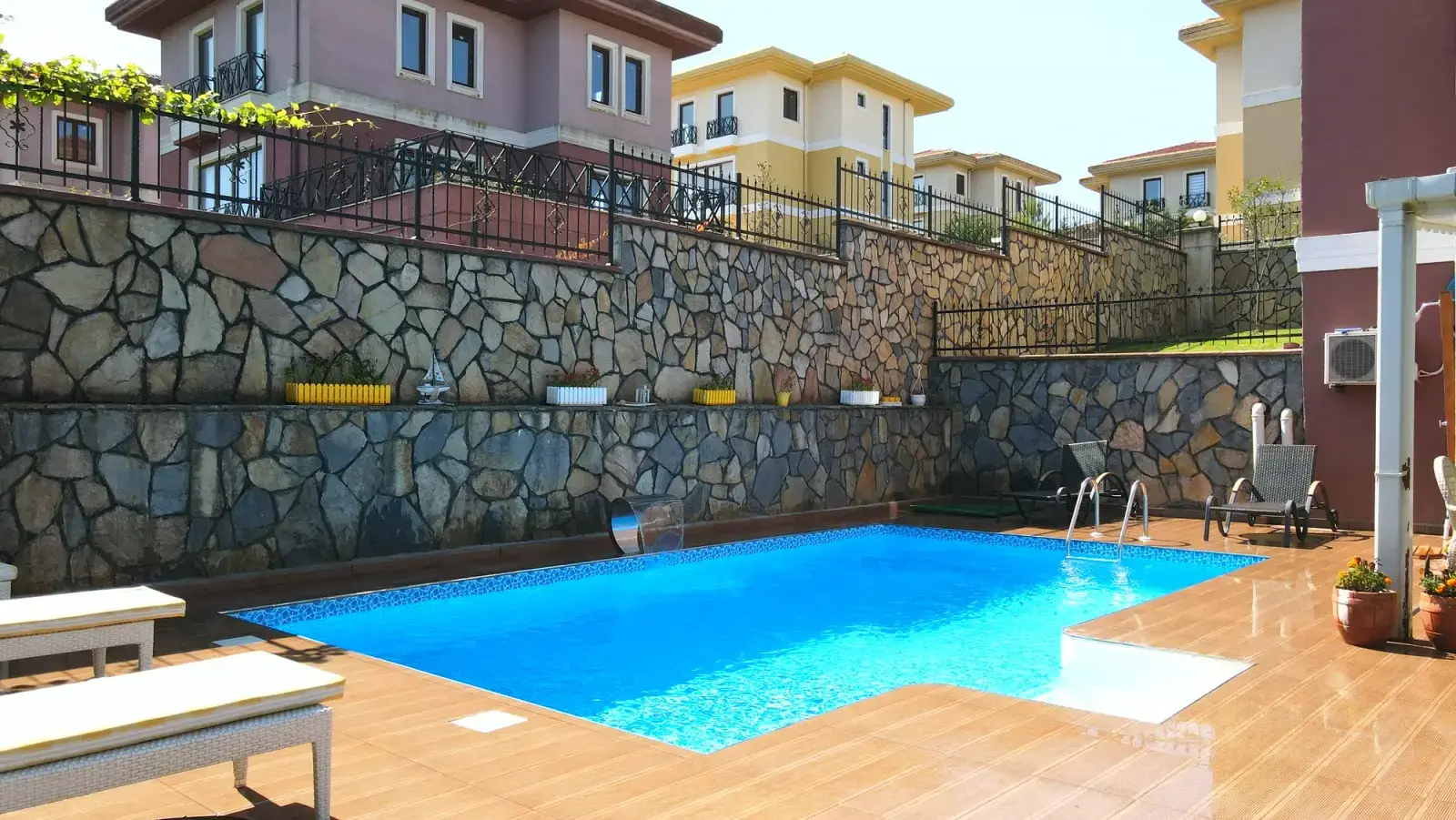 Taş duvarlı bahçede panel havuz